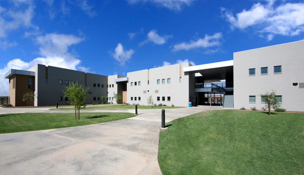 Modern Desert Meadows School facility with an expansive courtyard and clear blue skies.