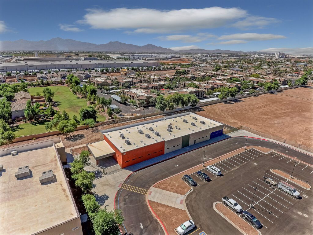 Aerial view of the Arizona Desert Elementary School building with a parking lot adjacent to a sports field, set against a backdrop of a residential area and mountains.