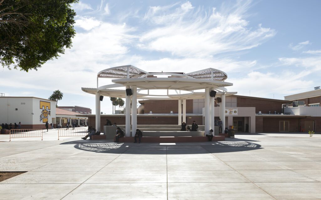 Modern outdoor pavilion on a sunny day with people seated at benches near Tolleson Union High School.